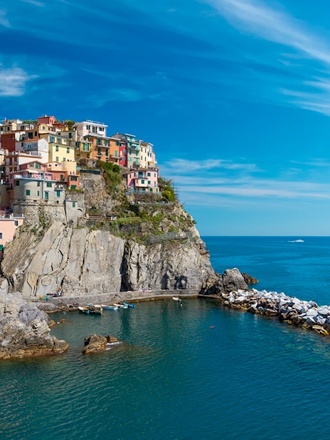 Colorful houses on a cliff in Cinque Terre with a boat in the sea, part of Florence to Cinque Terre tour.