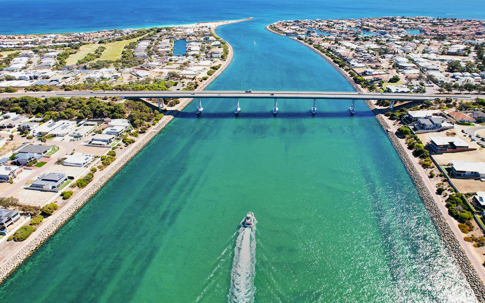 Giant & Dolphin Sightseeing Cruise passing under a bridge in a coastal town.