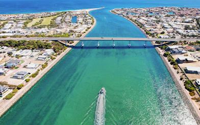 Giant & Dolphin Sightseeing Cruise passing under a bridge in a coastal town.