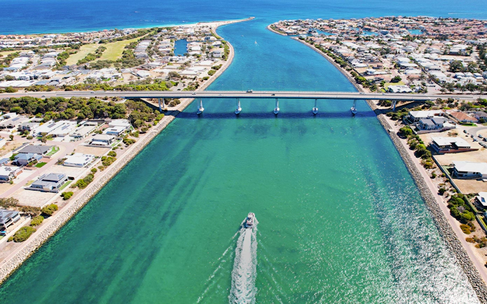 Giant & Dolphin Sightseeing Cruise passing under a bridge in a coastal town.