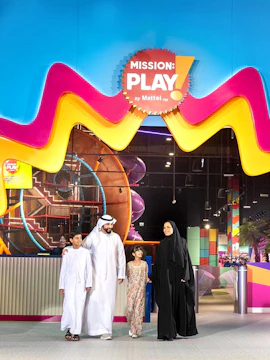 Family enjoying Mission: Play! by Mattel indoor play area with colorful structures.