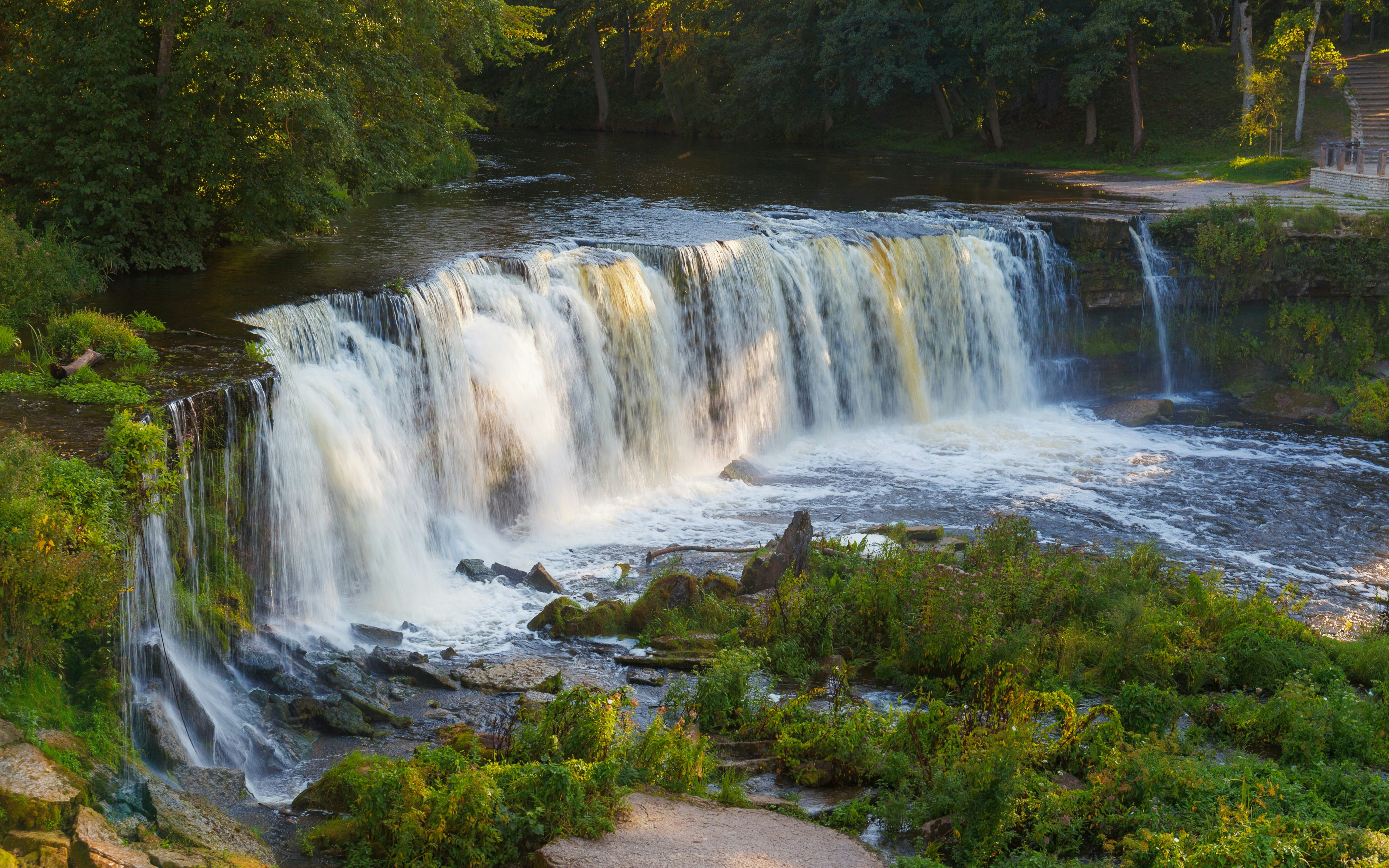 Keila Joa waterfall in summer, Estonia, surrounded by lush greenery.