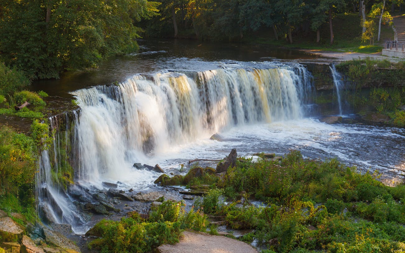 Keila Joa waterfall in summer, Estonia, surrounded by lush greenery.