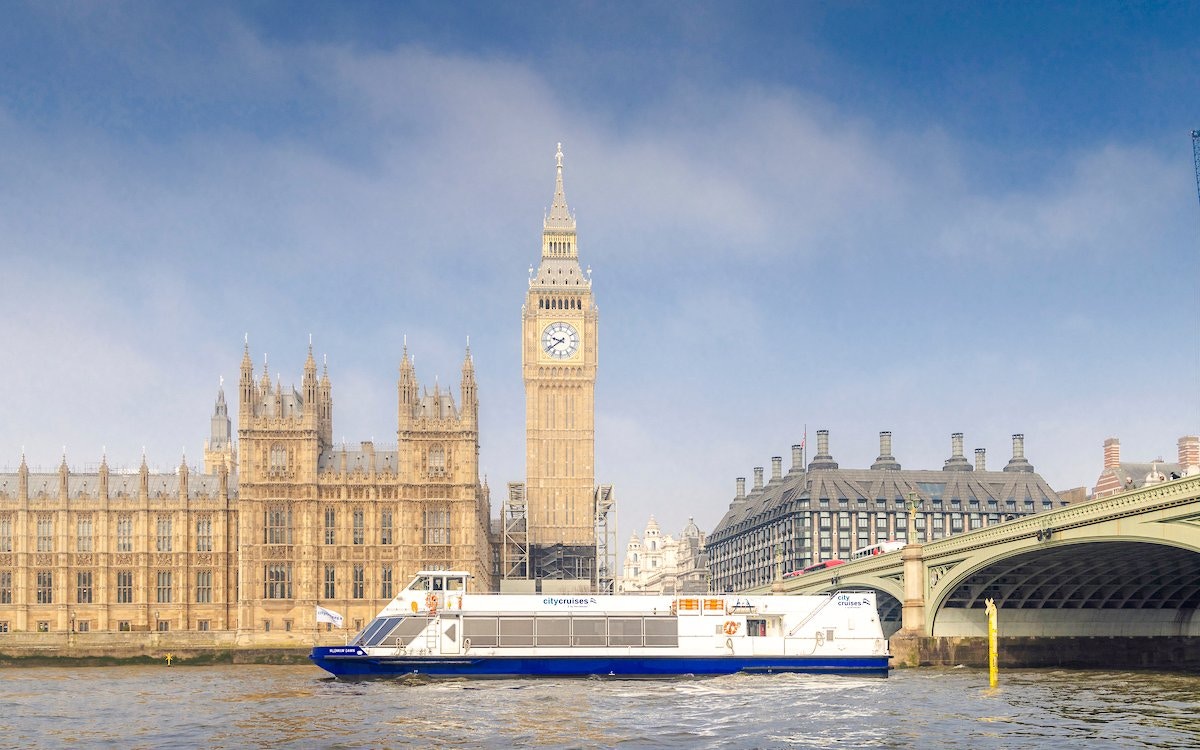 Cruise boat on the Thames near Westminster and Houses of Parliament, London.