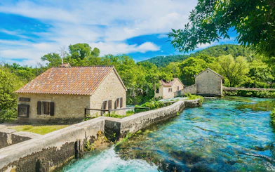 Traditional stone houses and historic watermills by a river in Krka National Park.
