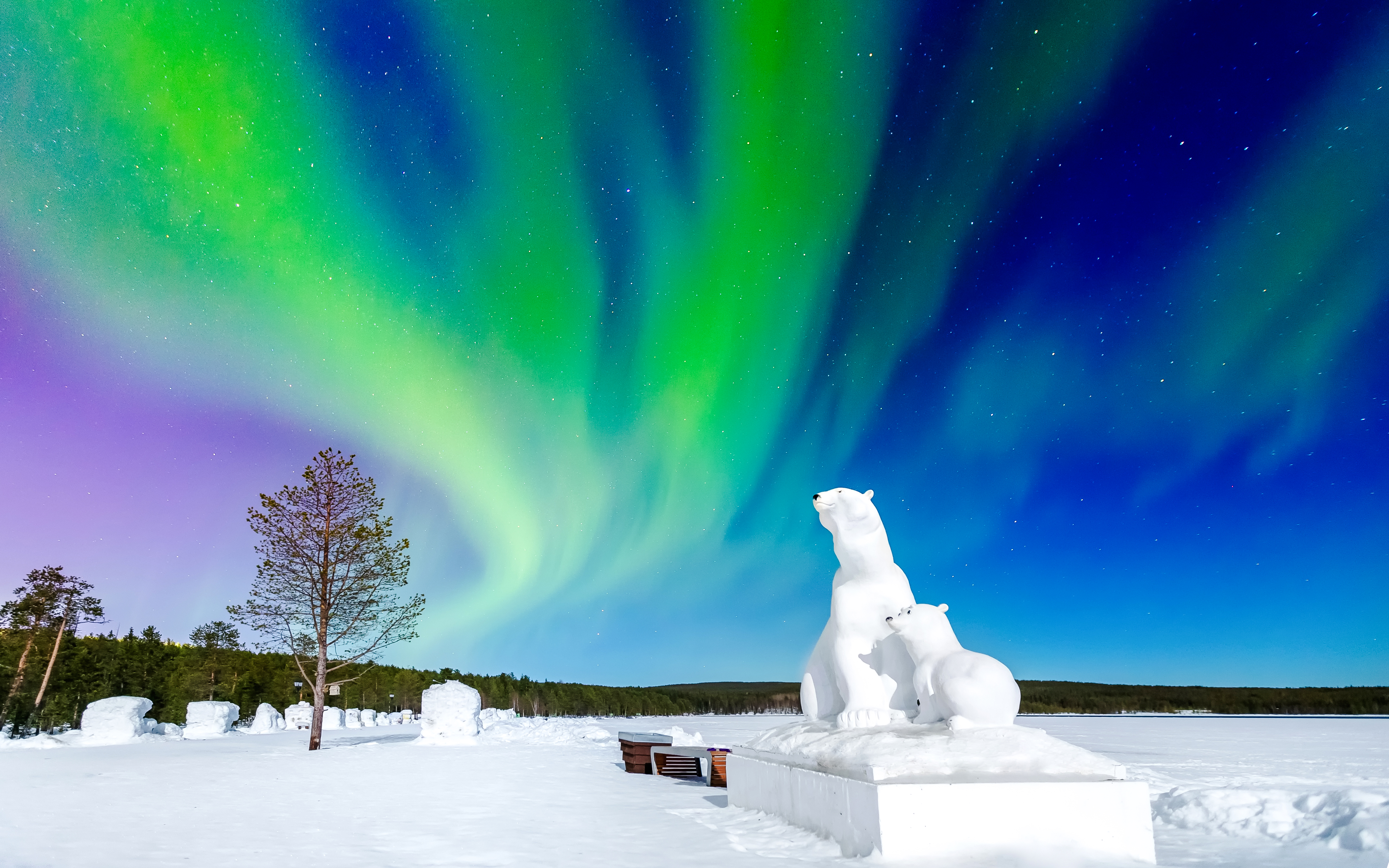Polar bear snow sculptures under aurora borealis in Arctic night sky.