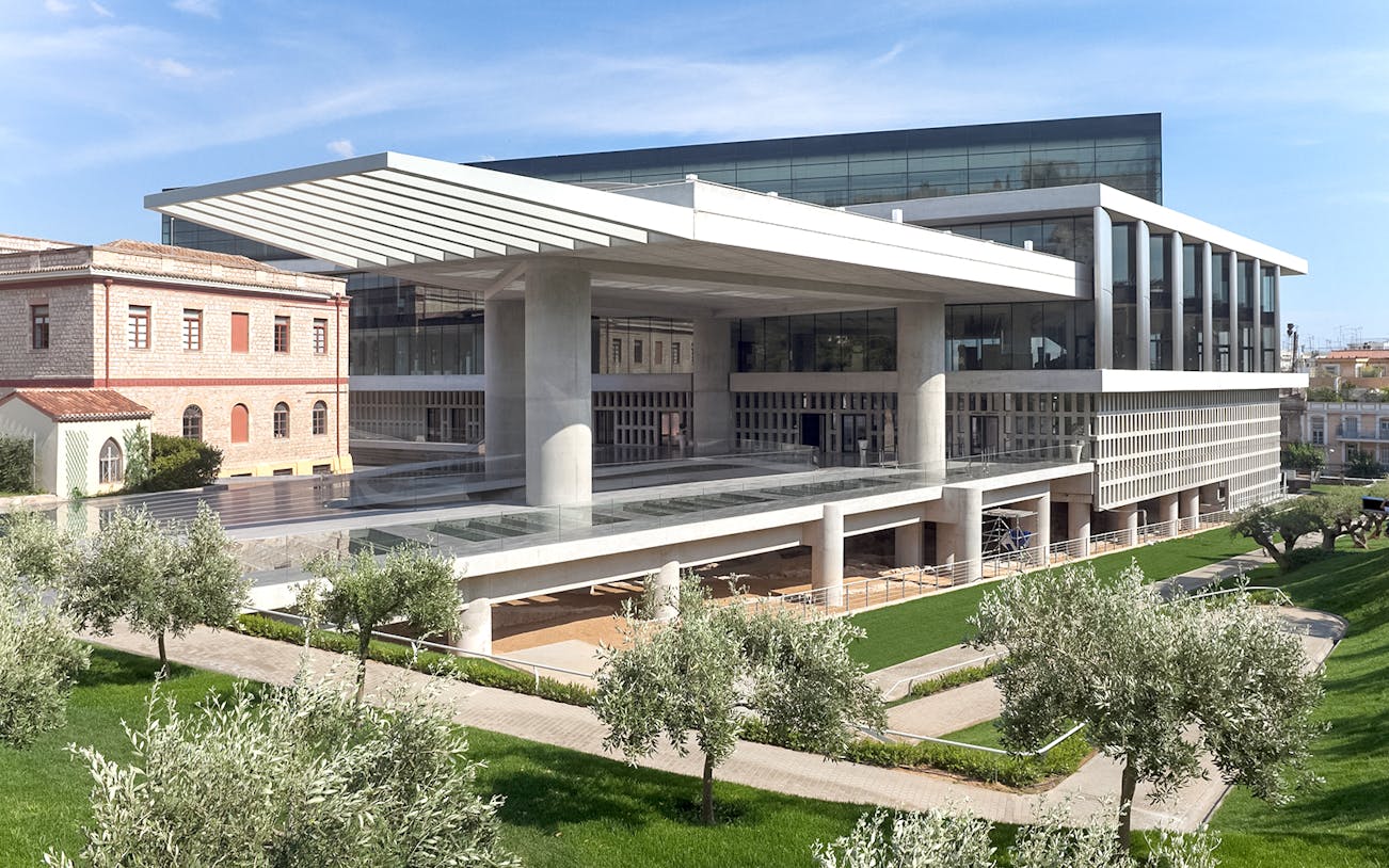 Acropolis Museum exterior with modern architecture and surrounding greenery in Athens, Greece.