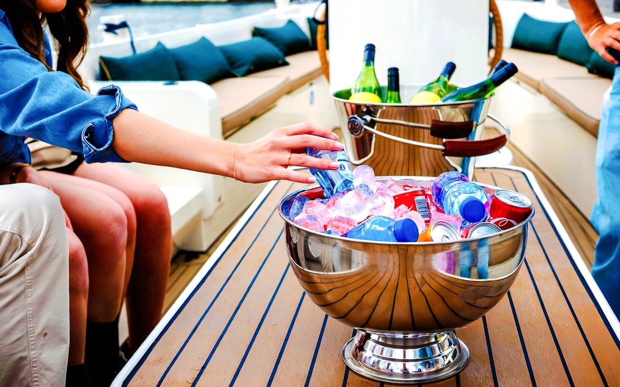 Hand reaching for drinks in an ice-filled bowl on an Amsterdam canal cruise boat.