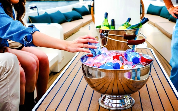 Hand reaching for drinks in an ice-filled bowl on an Amsterdam canal cruise boat.
