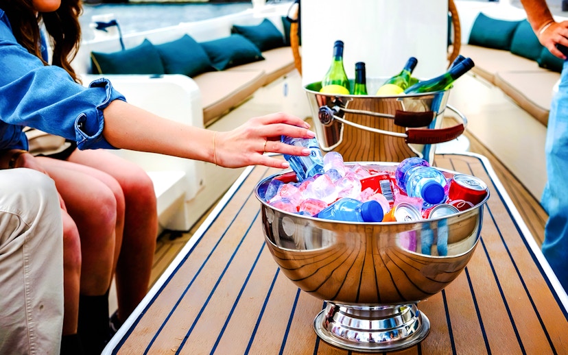Hand reaching for drinks in an ice-filled bowl on an Amsterdam canal cruise boat.