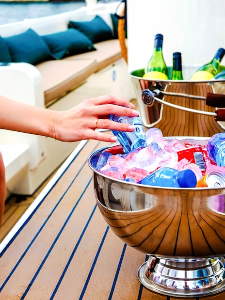 Hand reaching for drinks in an ice-filled bowl on an Amsterdam canal cruise boat.