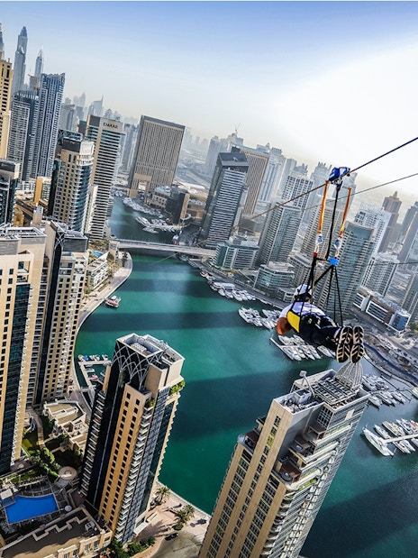 Ziplining over Dubai Marina with skyscrapers and waterfront views.