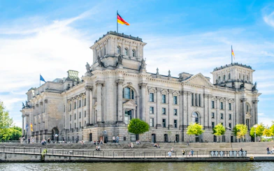 Reichstag building in Berlin with German flags and people on the steps.