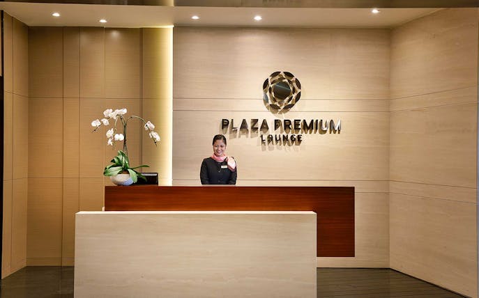 Plaza Premium Lounge reception desk at T1 International Departures with staff member.