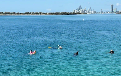 Kayakers and snorkelers in clear waters with Gold Coast skyline in the background.