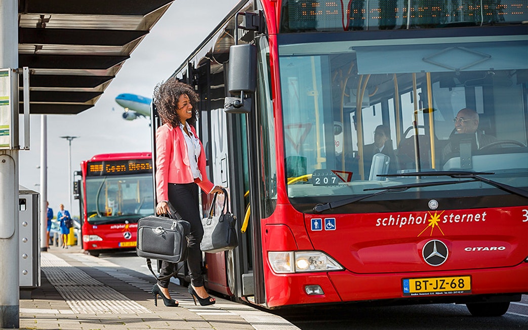 Passenger boarding red bus at Schiphol Airport for Amsterdam Airport Express route.
