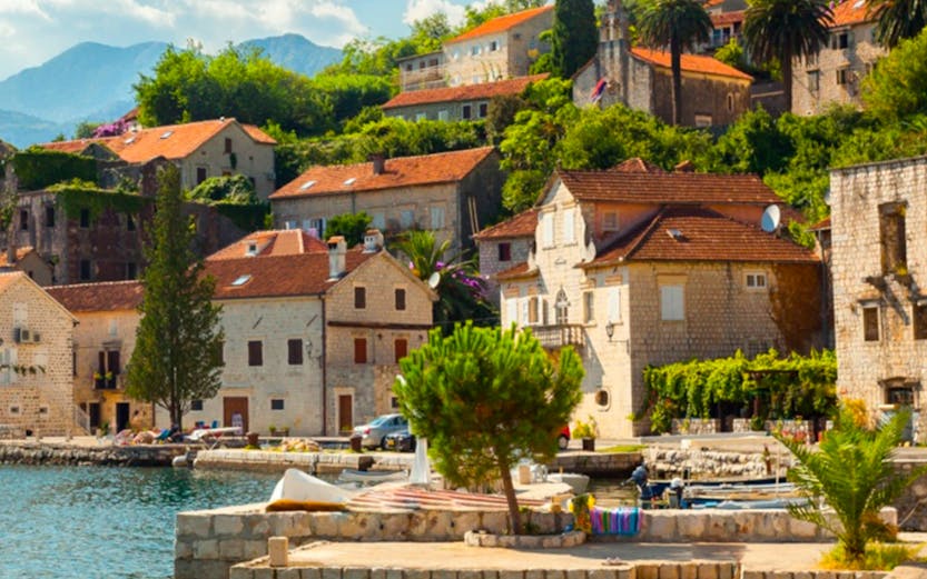 Coastal village with stone houses and red roofs along the Dubrovnik to Montenegro route.