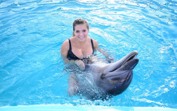 Woman swimming with dolphin at Dolphin World Egypt, Hurghada.