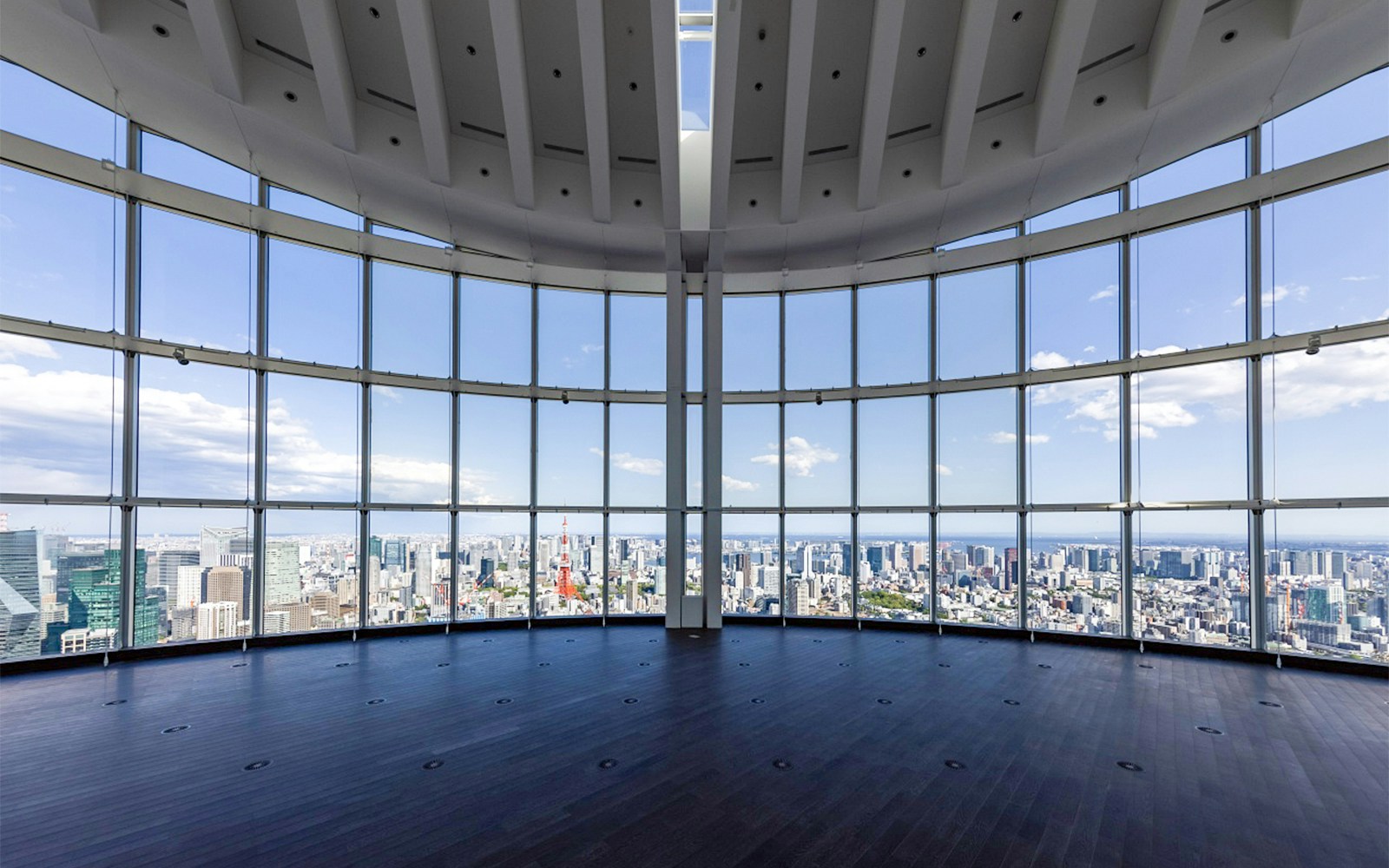 Visitors enjoying the panoramic view of Tokyo from Roppongi Hills Observation Deck, with Mori Art Museum in the background.