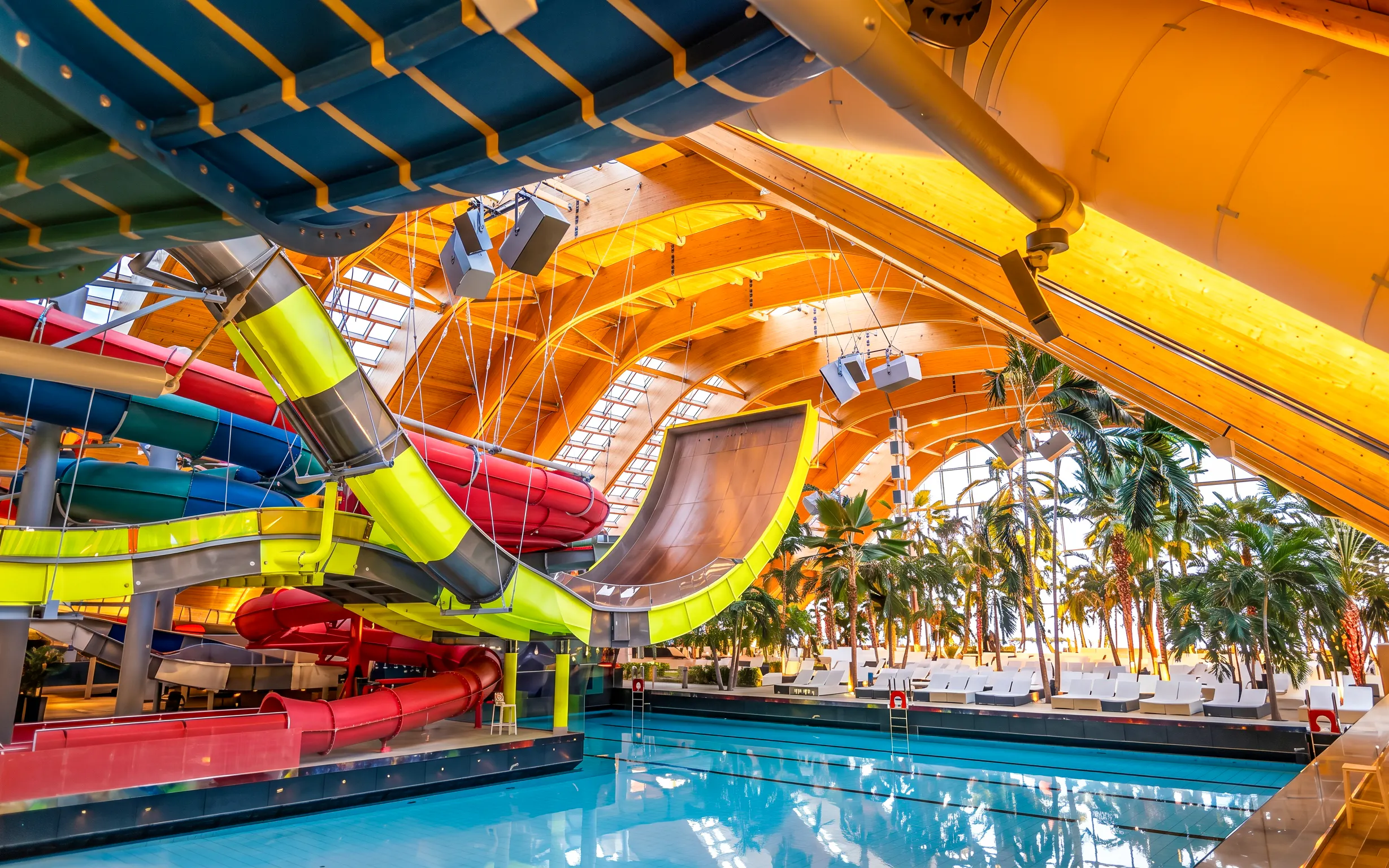 Colorful water slides at Therme Bucuresti indoor pool area.