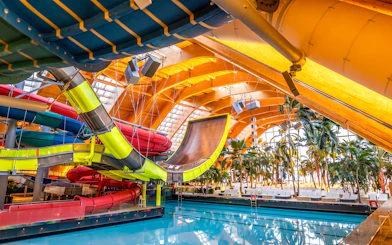 Colorful water slides at Therme Bucuresti indoor pool area.