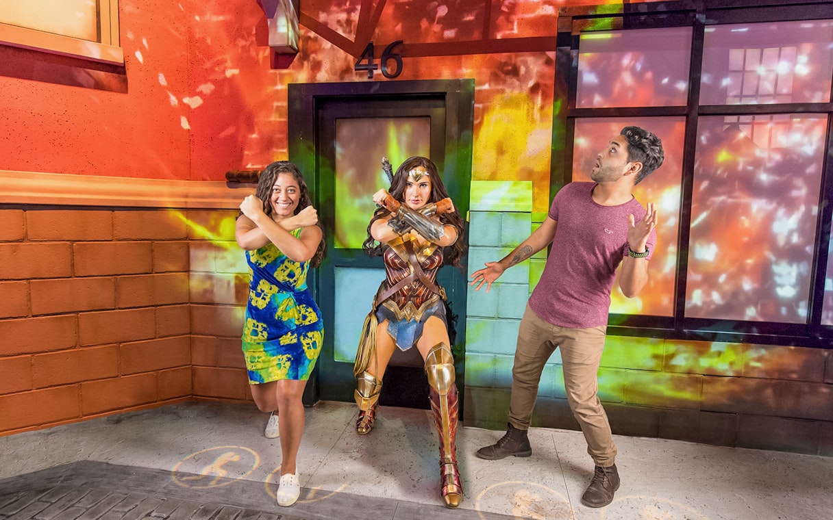 Tourist posing with Wonder Woman wax statue at a museum exhibit.