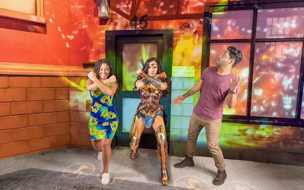 Tourist posing with Wonder Woman wax statue at a museum exhibit.