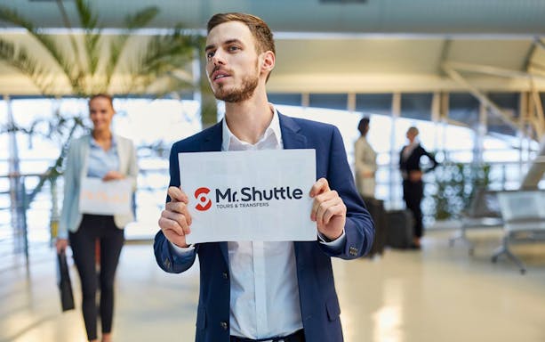 Man holding Mr. Shuttle sign at Gdansk Airport for transfers to Gdynia city.