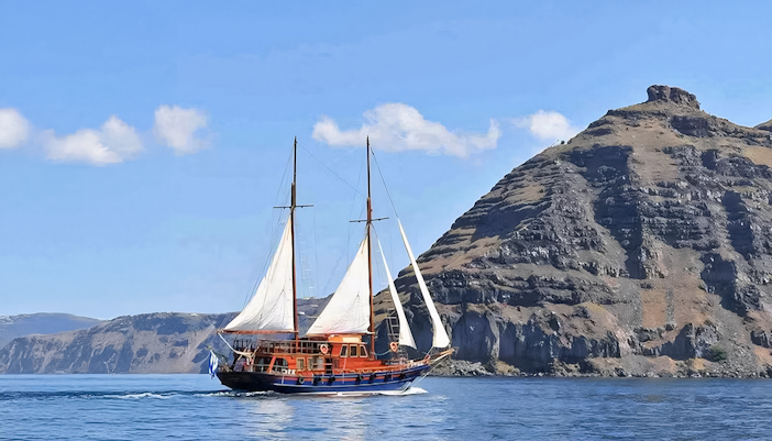 Sailing boat near volcanic cliffs on Santorini Volcanic Islands tour.