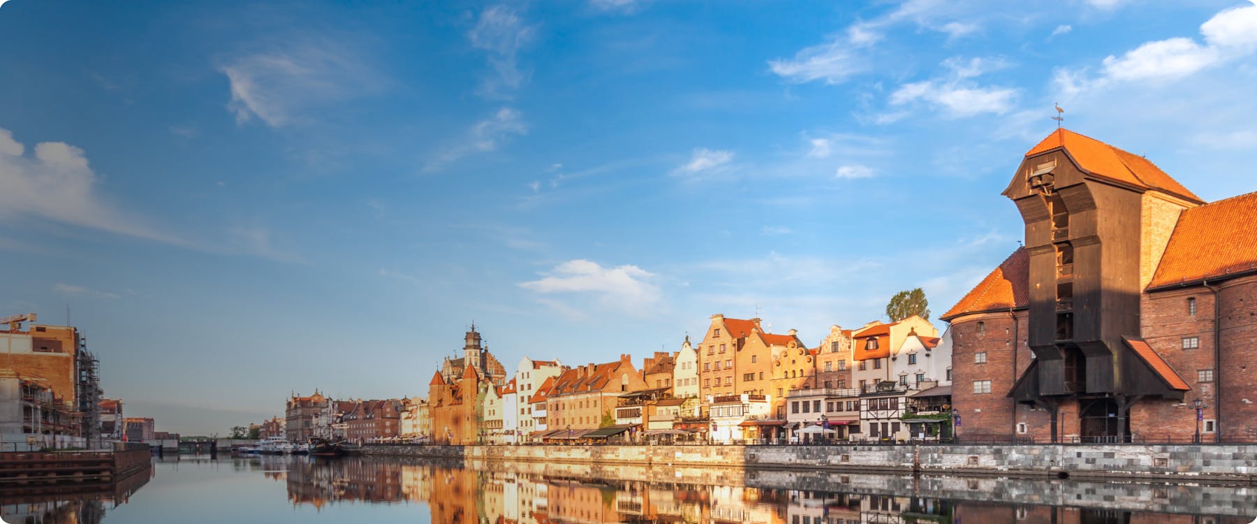 Gdansk waterfront with historic buildings and the medieval crane reflected in the Motlawa River.