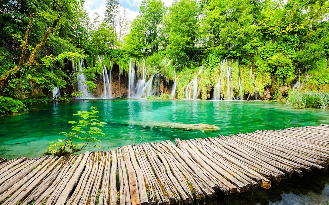 Wooden path over turquoise water and waterfalls at Plitvice Lakes National Park, Croatia.