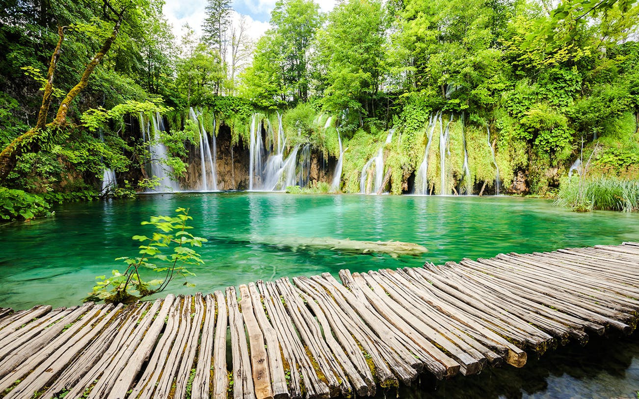 Wooden path over turquoise water and waterfalls at Plitvice Lakes National Park, Croatia.