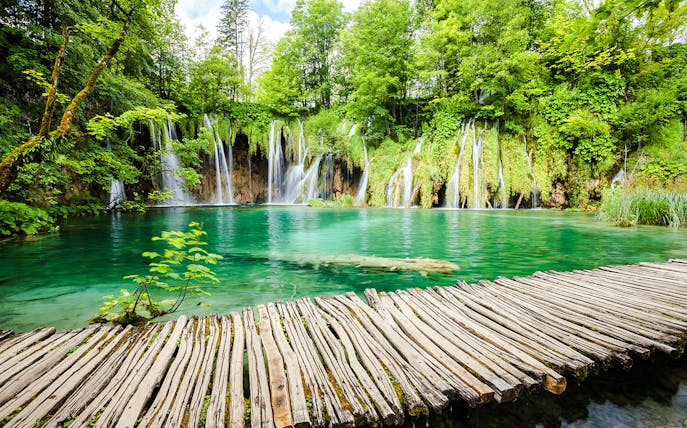 Wooden path over turquoise water and waterfalls at Plitvice Lakes National Park, Croatia.