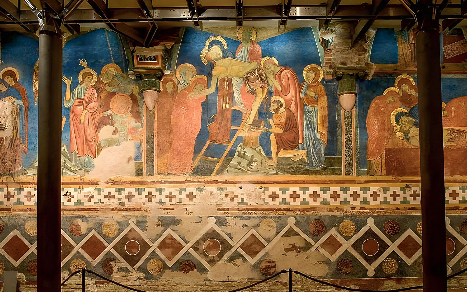 Tour group viewing frescoes in Siena Cathedral Crypt, Italy, with vibrant religious scenes.