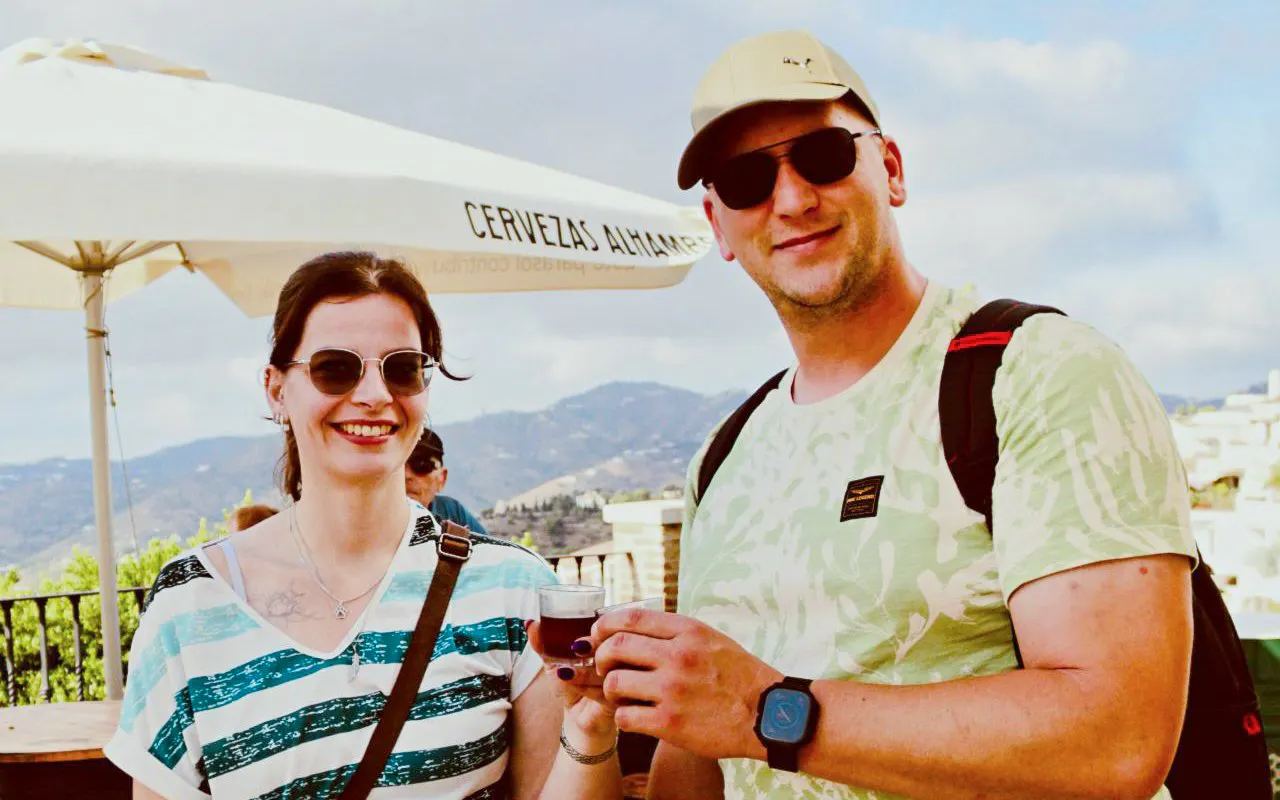Couple enjoying drinks with a view of Frigiliana's scenic mountains.