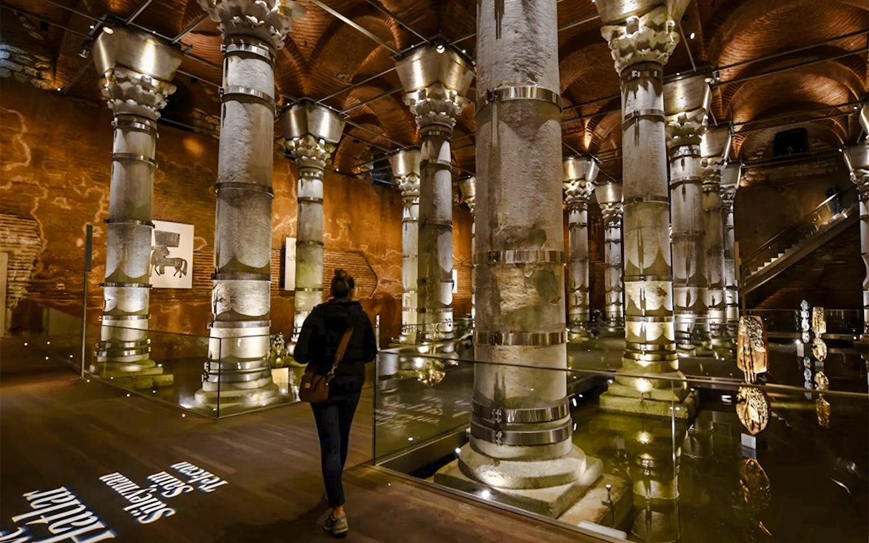 Visitors exploring Theodosius Cistern with illuminated columns in Istanbul.