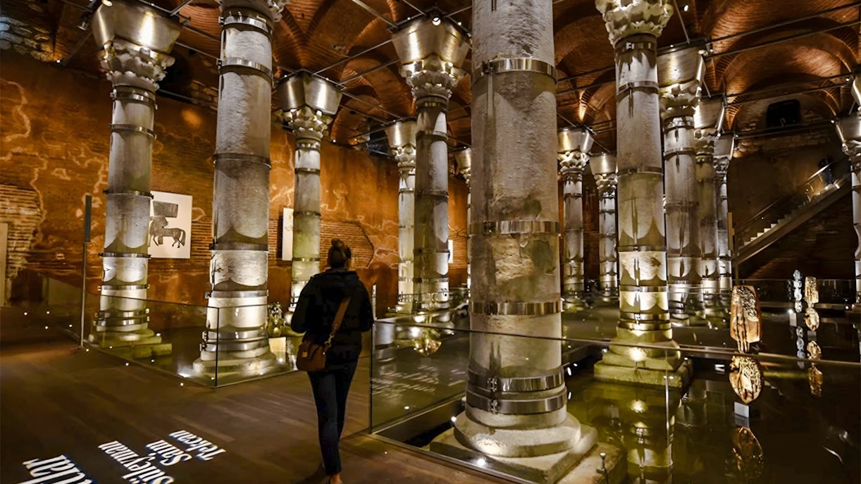 Visitors exploring Theodosius Cistern with illuminated columns in Istanbul.