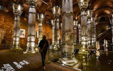 Visitors exploring Theodosius Cistern with illuminated columns in Istanbul.