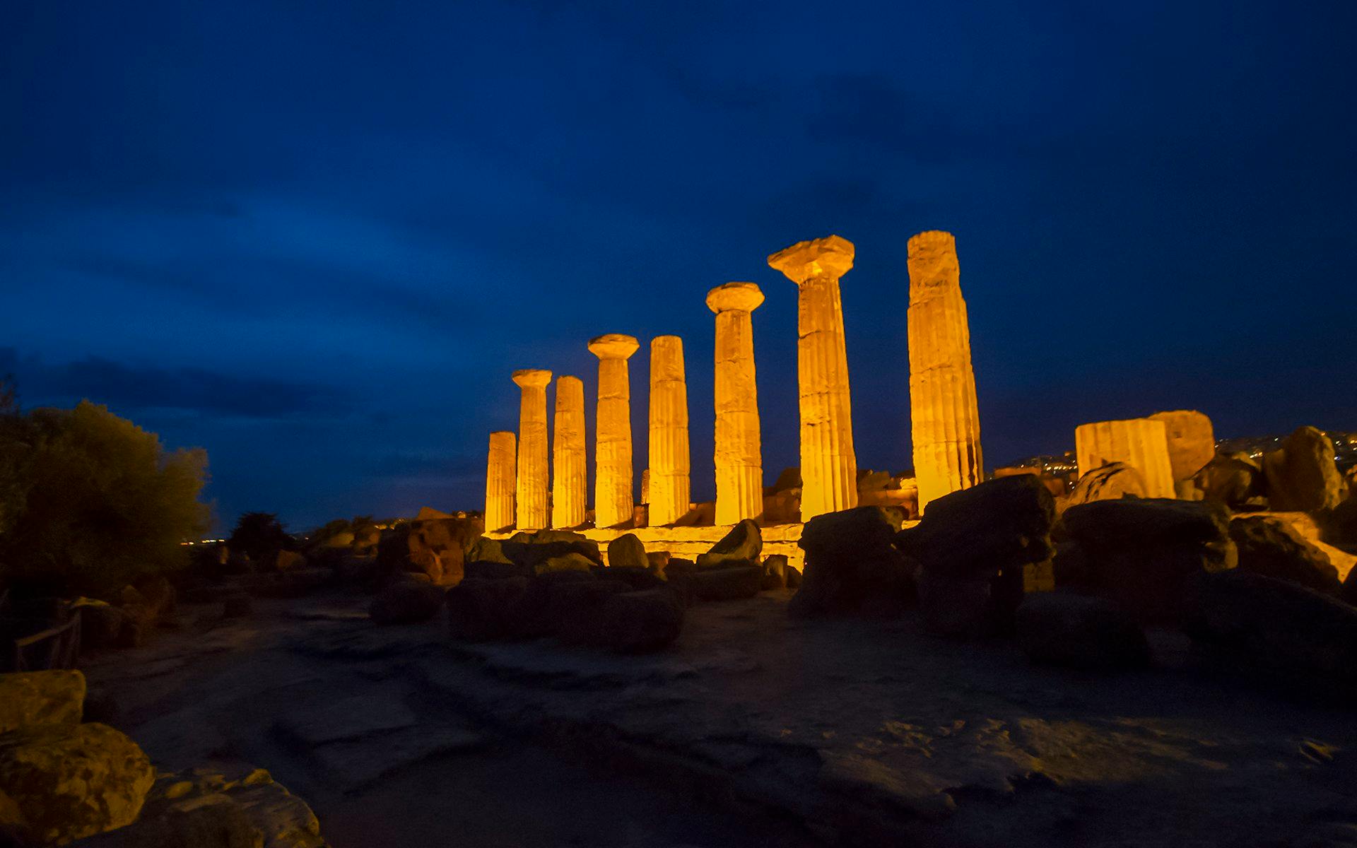 Ancient Greek temple columns illuminated at night in the Valley of the Temples, Italy.