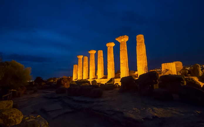 Ancient Greek temple columns illuminated at night in the Valley of the Temples, Italy.