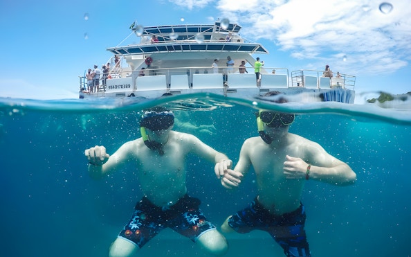 Tourists snorkelling near a catamaran during Buzios Full Day Tour.