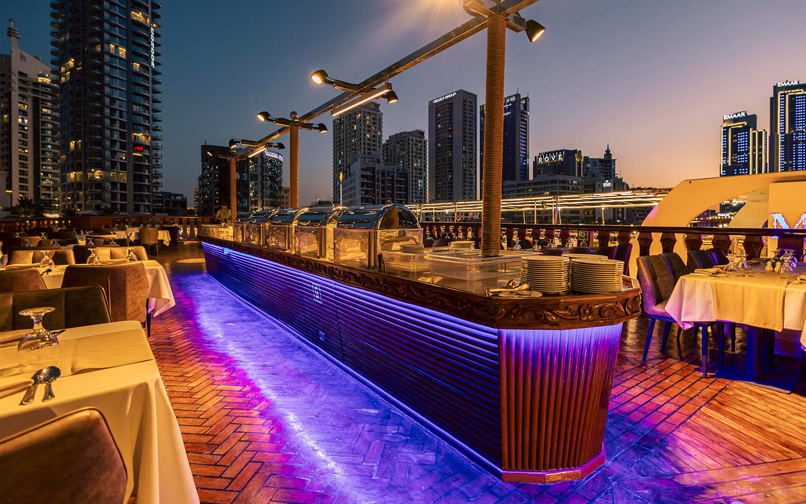 Dinner setup on Alexandra Dhow Cruise with city skyline view, Dubai Marina.