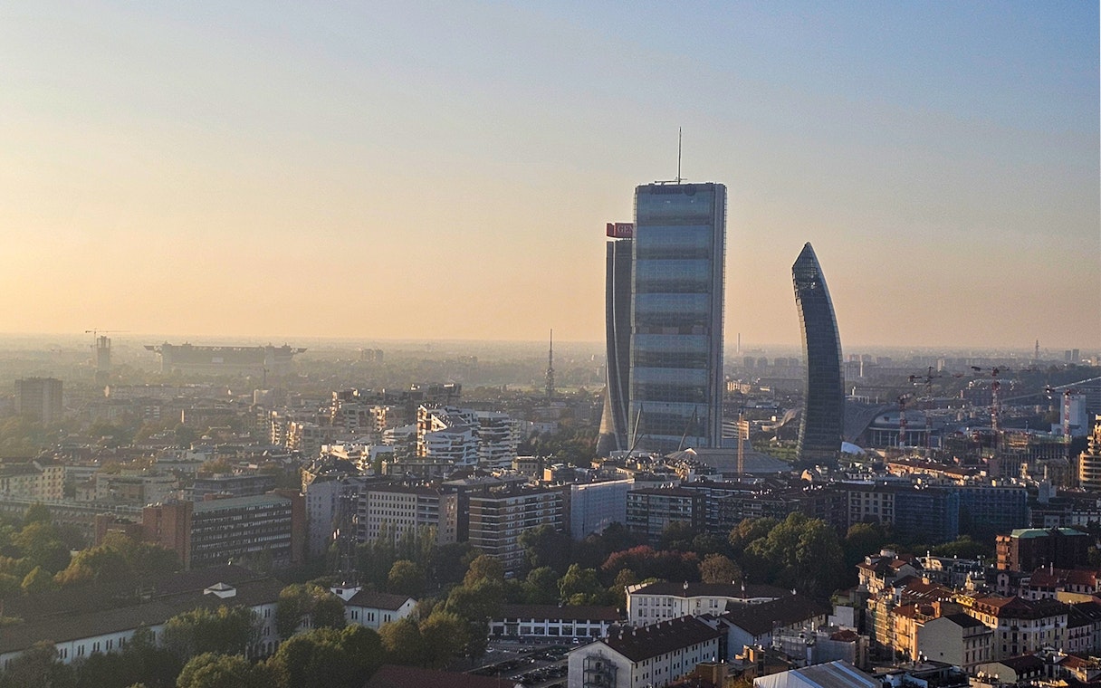 Milan skyline view with Torre Branca and modern skyscrapers at sunset.
