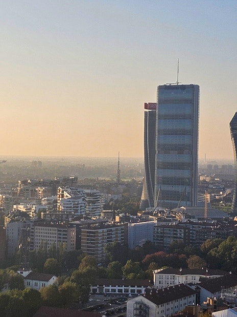 Milan skyline view with Torre Branca and modern skyscrapers at sunset.