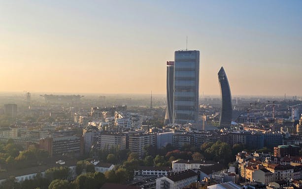 Milan skyline view with Torre Branca and modern skyscrapers at sunset.