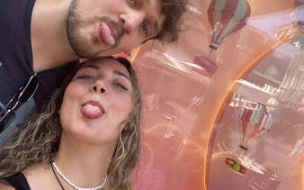Two people making faces in front of a window display with hot air balloons in Zürich.