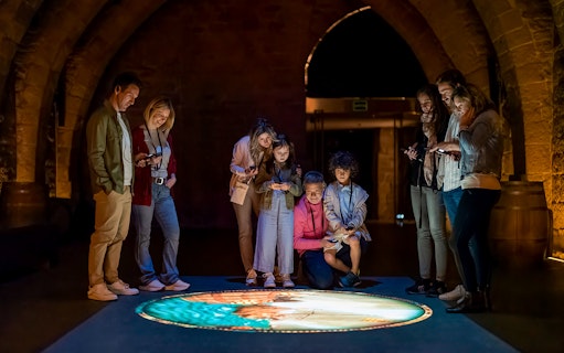 Visitors engaging with interactive display at Món Sant Benet medieval experience.