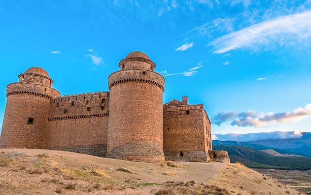 Guadix castle with round towers under a blue sky, part of the Granada full-day tour.