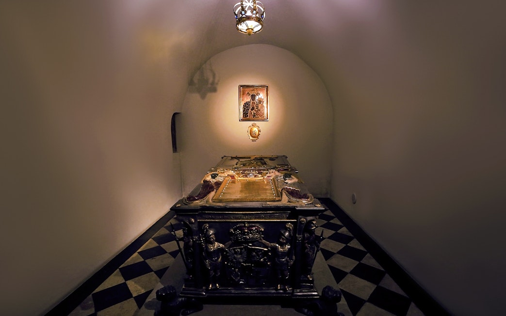 Crypt interior under Silver Bells Tower at Wawel Cathedral, featuring an ornate tomb.