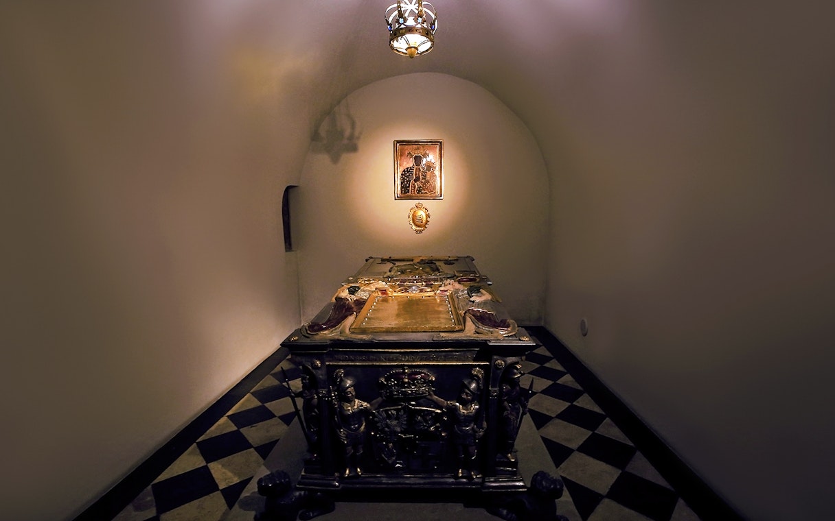 Crypt interior under Silver Bells Tower at Wawel Cathedral, featuring an ornate tomb.